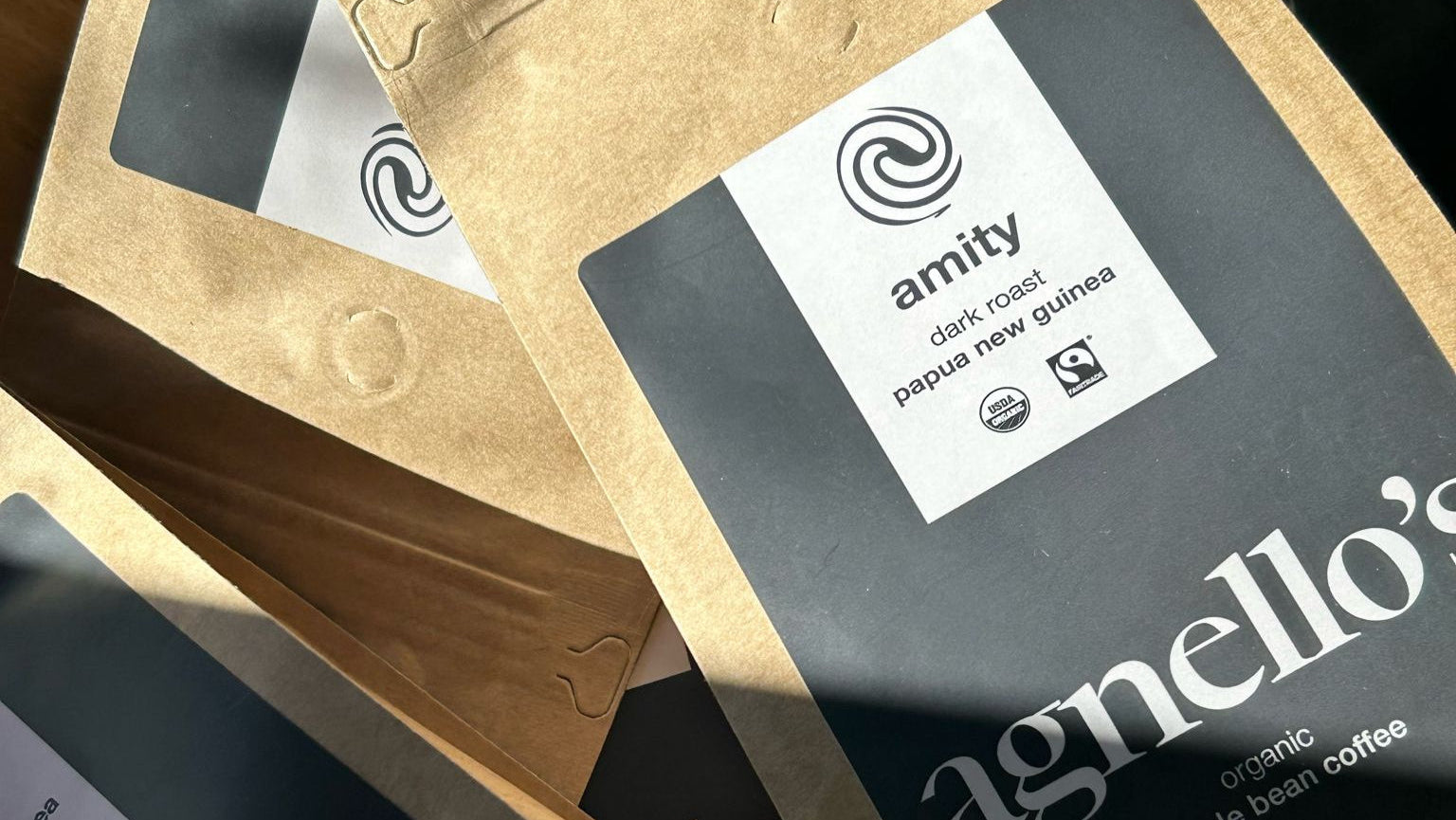 Agnello's coffee packages with visible branding on a wooden surface